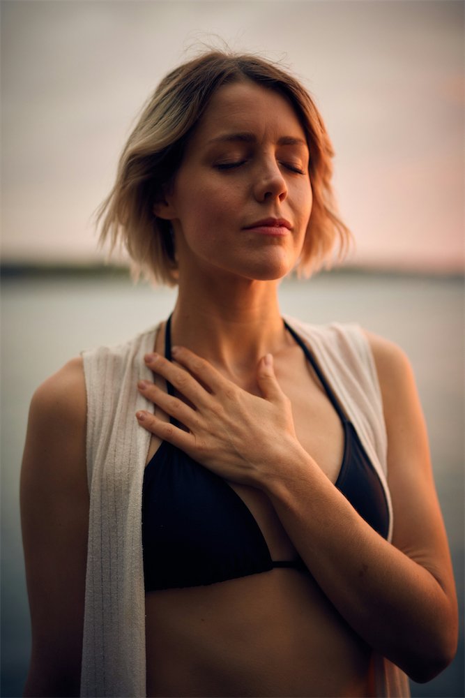 Woman meditating by a lake at sunset